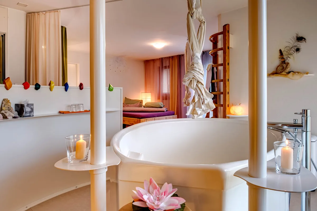 Bild eines Geburtspools, von der Decke hängt ein Tuch mit Knoten, um den Pool hat es Säulen.